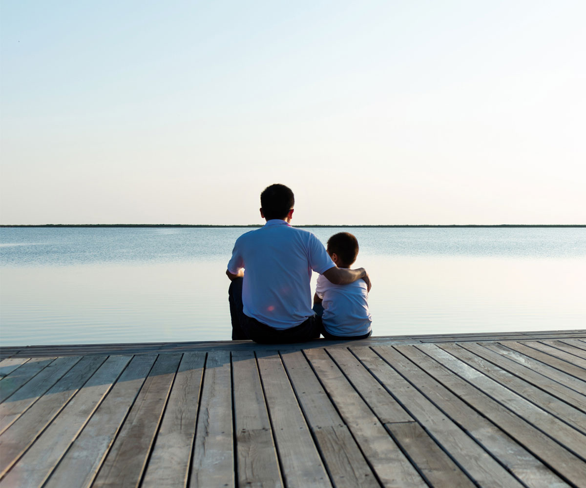 Father with his son enjoying lake view